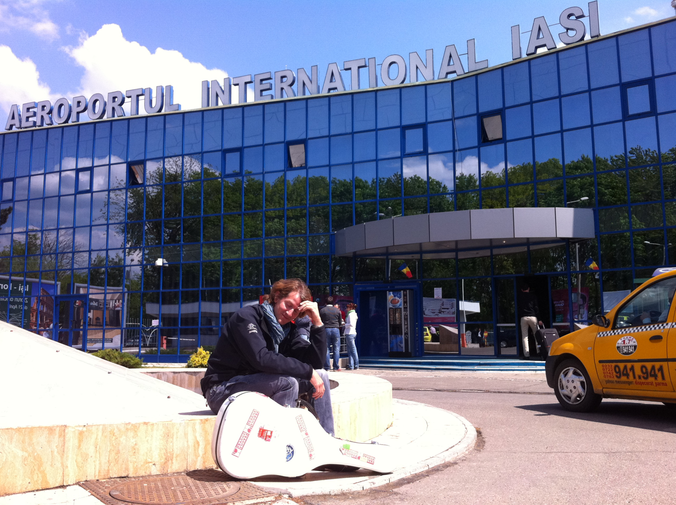 Benjamin Carmona sitting outside Iași International Airport with his guitar case